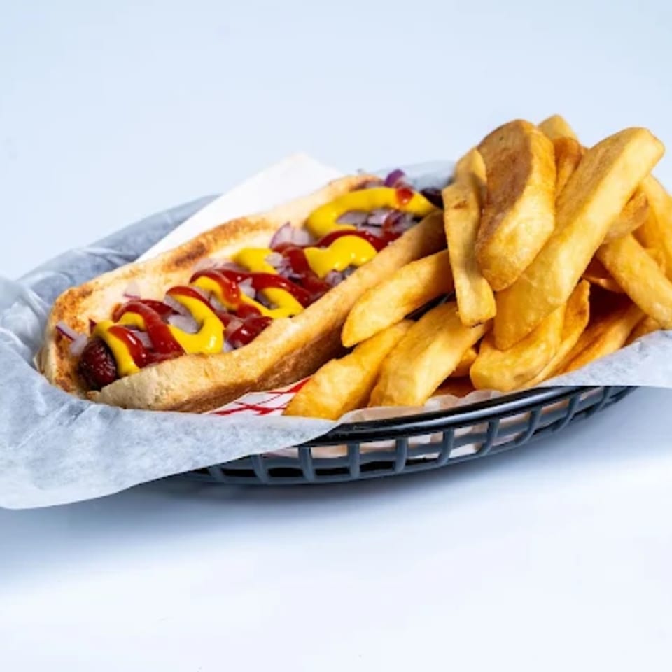 Halal Eatery hot dog with ketchup, mustard, onions, and a side of thick-cut fries in a basket.